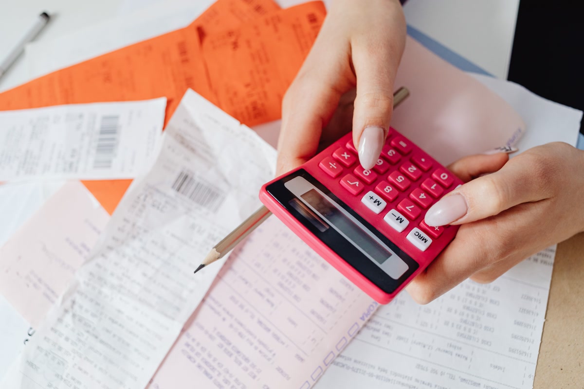Hands using calculator with receipts and bills for pet budget planning