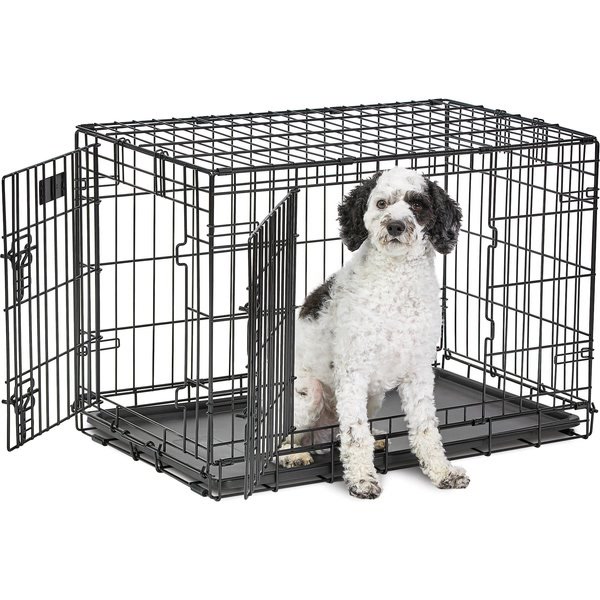 Small dog sitting comfortably inside a wooden furniture-style dog crate end table