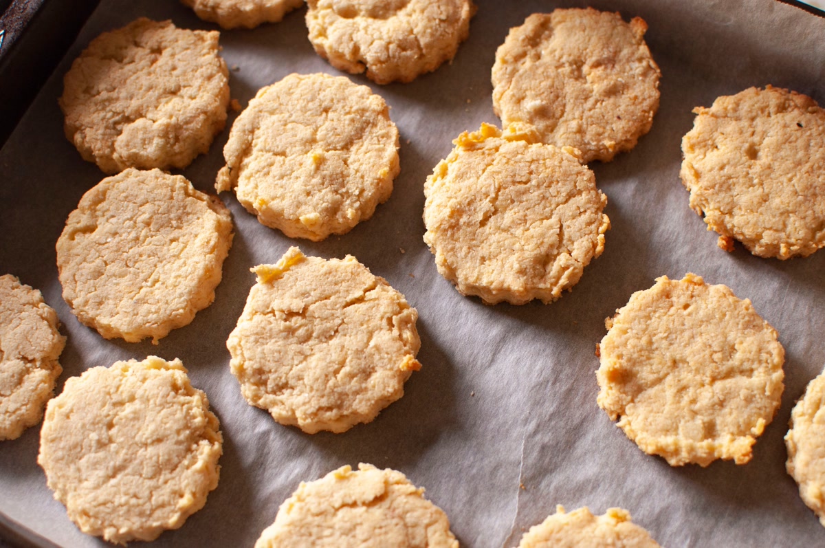 Homemade golden brown dog biscuits cooling on parchment lined baking tray