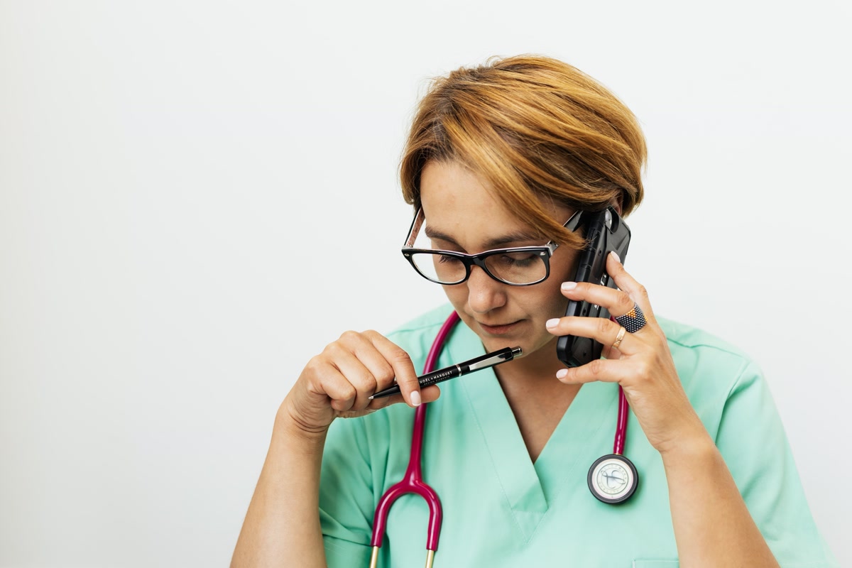 Female medical professional in scrubs talking on phone to schedule veterinary appointment