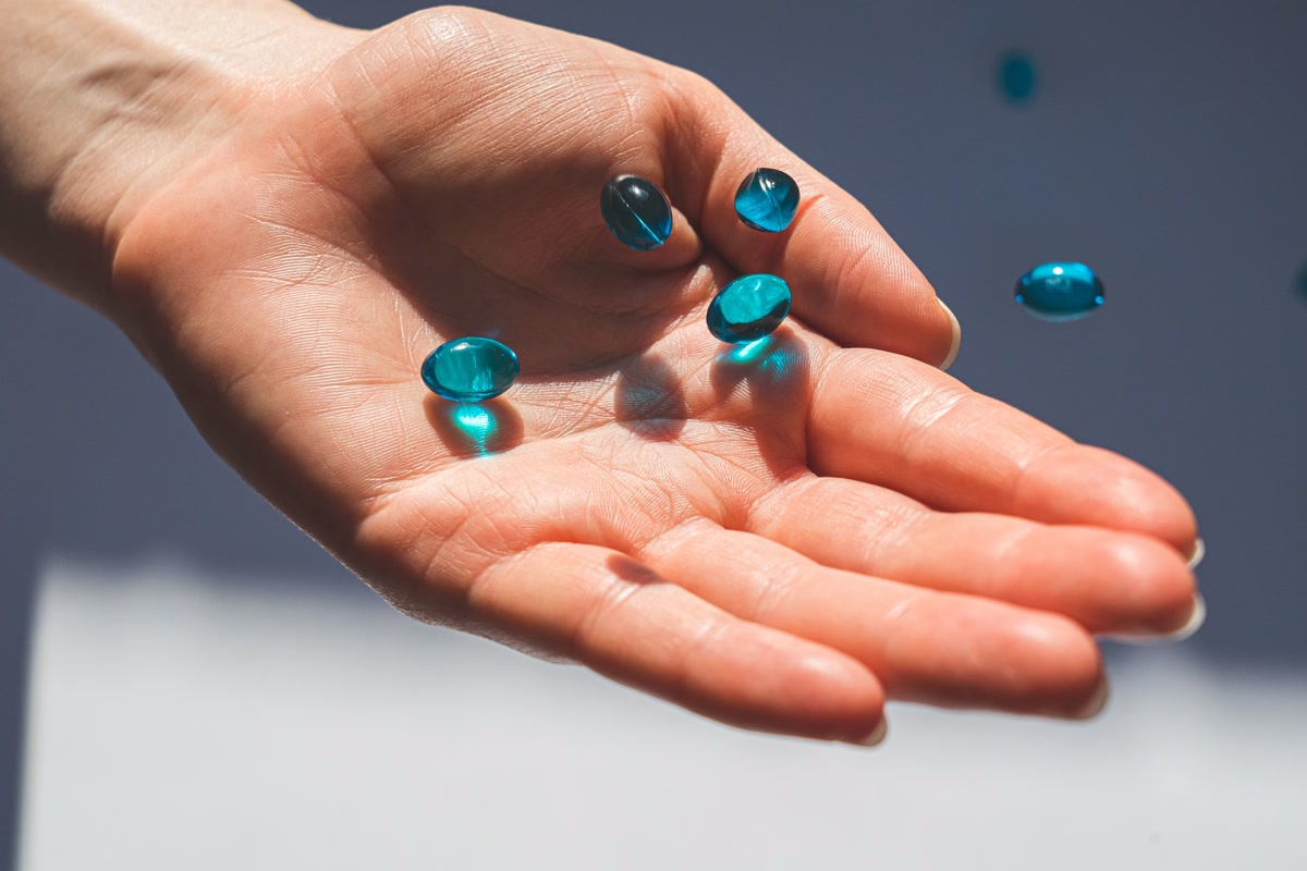 Hand holding blue gel capsule pills for administering dog medication supplements