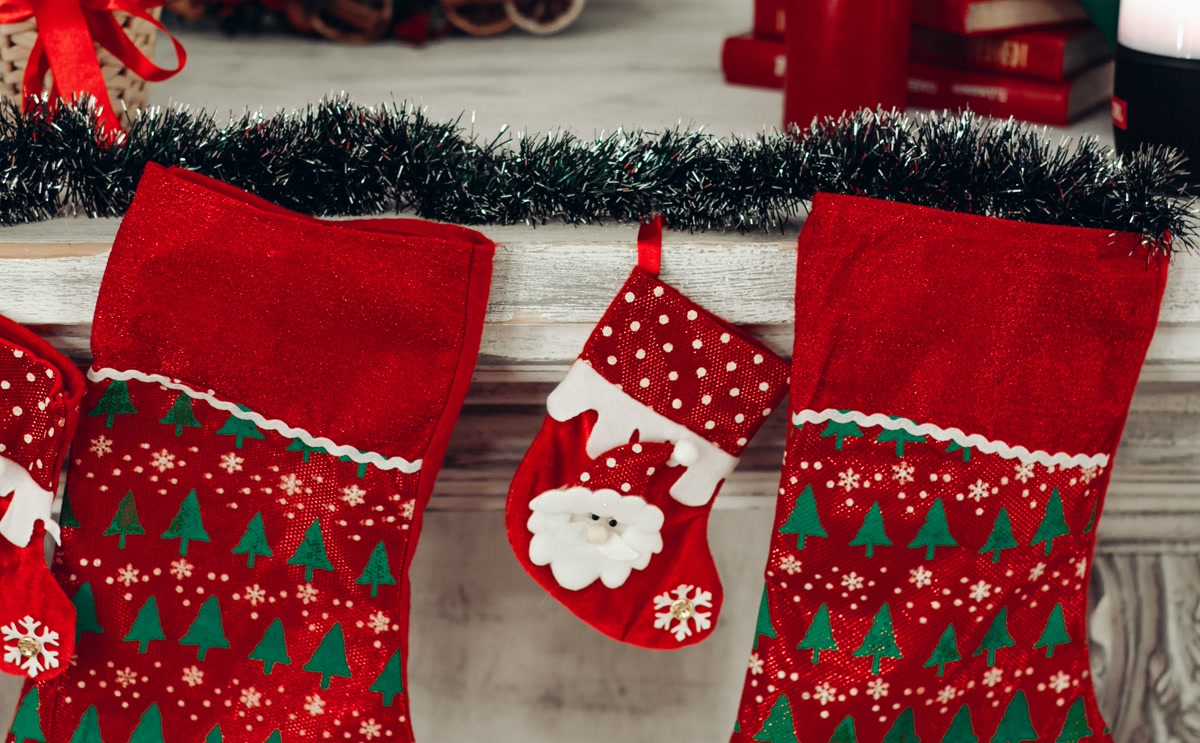 Red Christmas stockings including small pet stocking hanging on fireplace mantle