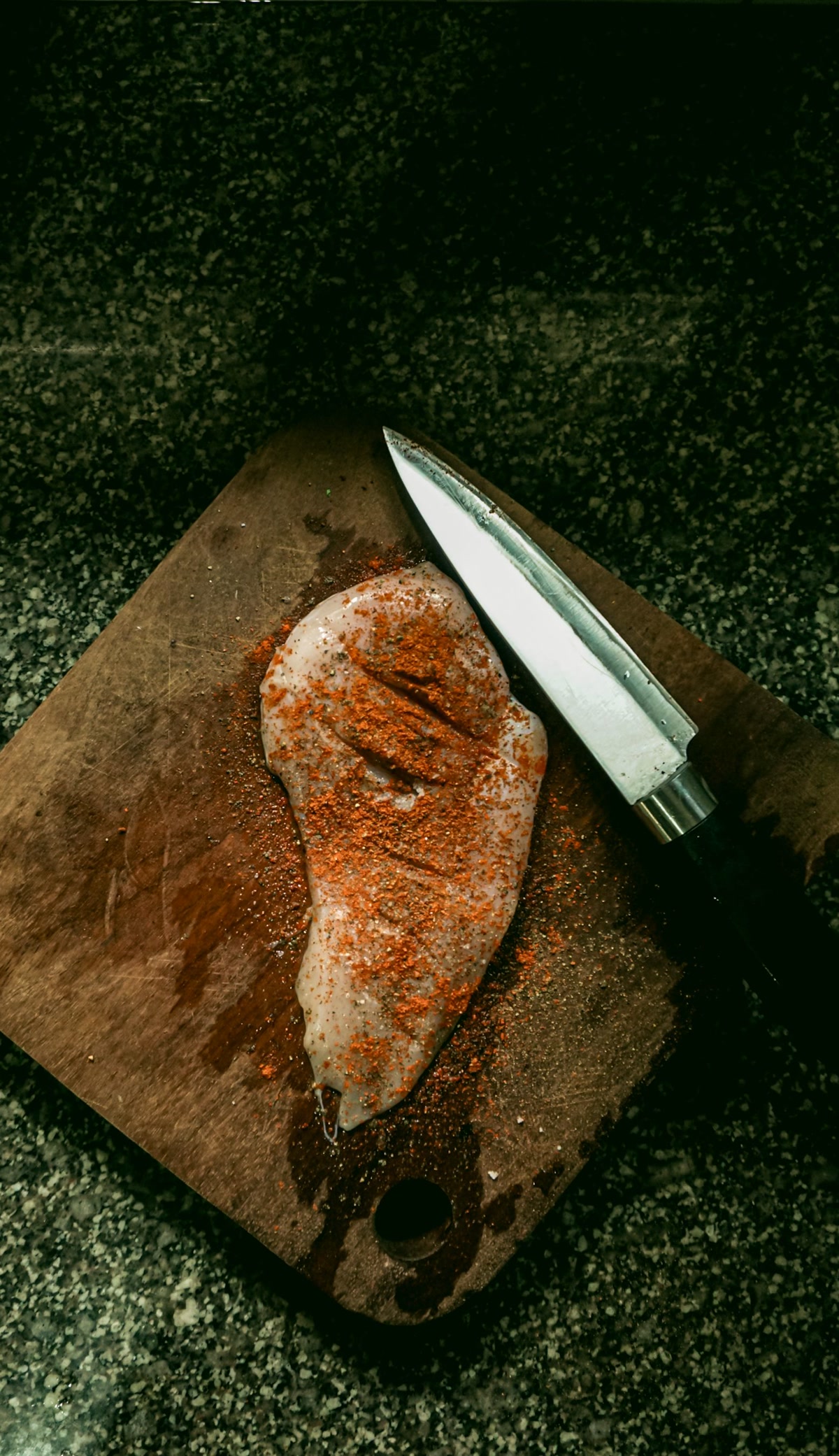 Raw chicken breast on cutting board for homemade dog food preparation