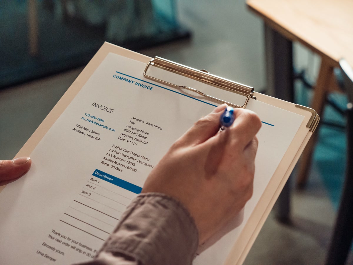 Person holding veterinary invoice clipboard showing medical costs and billing